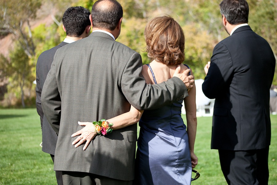 a woman and man wrap arms around each other's back as they get ready to participate in an outdoor wedding processional