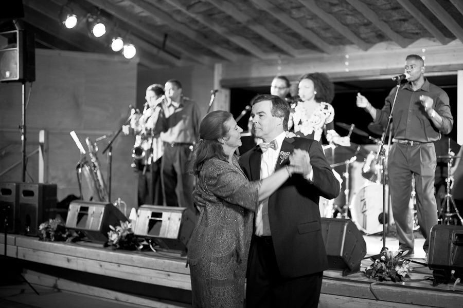 black and white photo of a man and woman slow-dancing in front of a stage with a live band
