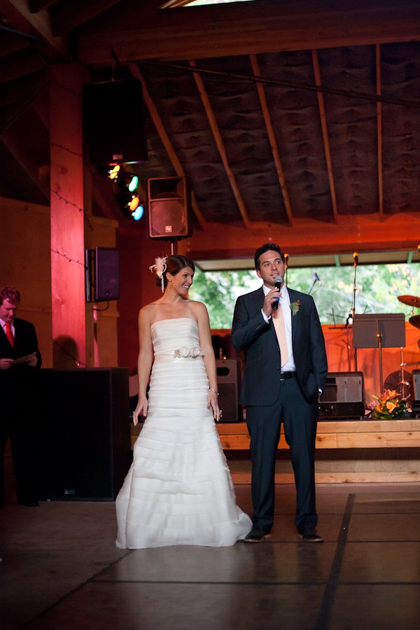 a bride and groom give a speech in front of a stage
