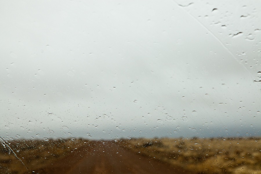 a barren landscape on a rainy day as seen through a car windshield