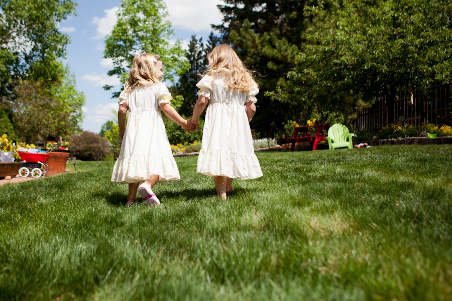 two girls in yellow dresses hold hands and walk