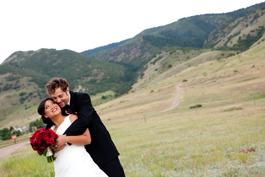 a groom puts his arms around a bride in front of the mountains