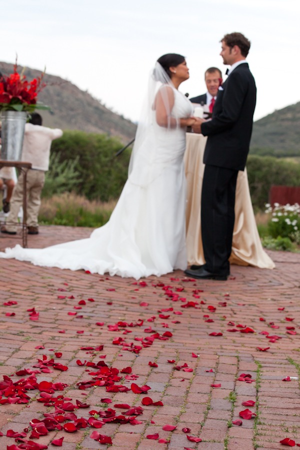roses sit on a brick path in front of a bride and groom