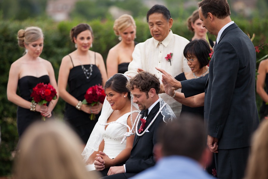bride and groom sit down while being blessed by a man and woman