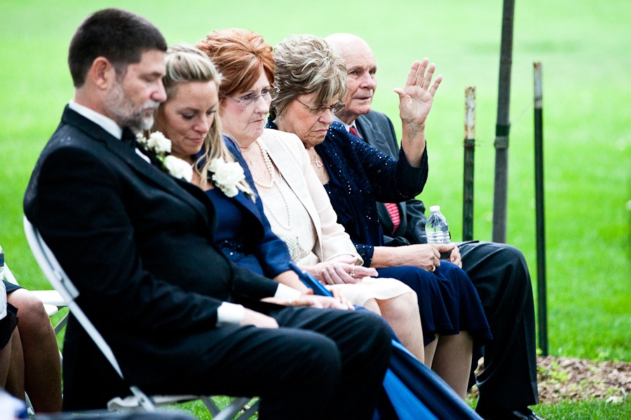 a woman raises her hand in prayer during an outdoor wedding ceremony