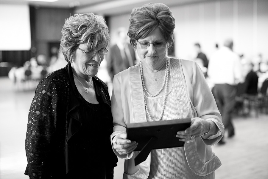 black and white image of two wedding guests looking at a photo