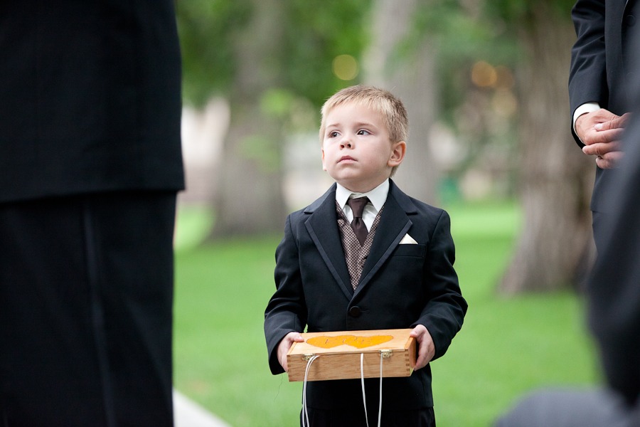 young boy in suit with box looks up during outdoor wedding ceremony