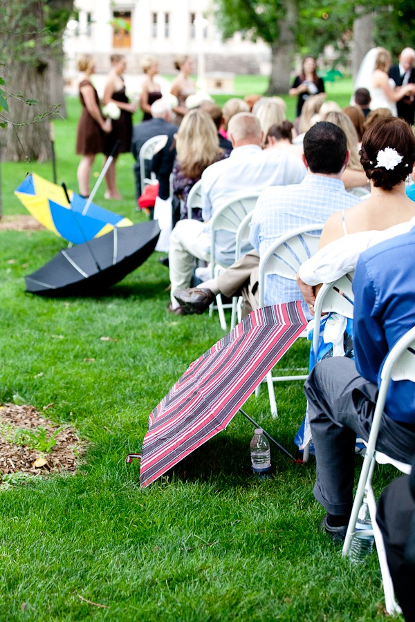 umbrellas dot a green yard during an outdoor wedding ceremony