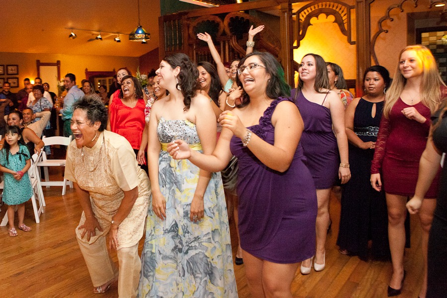 women line up to catch a wedding bouquet while laughing