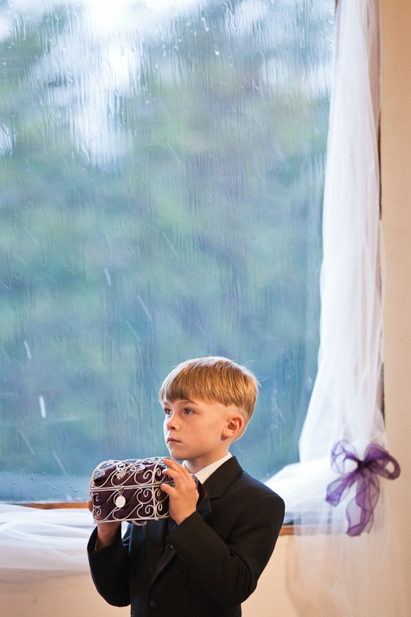 ring bearer holds a box in front of a rainy window