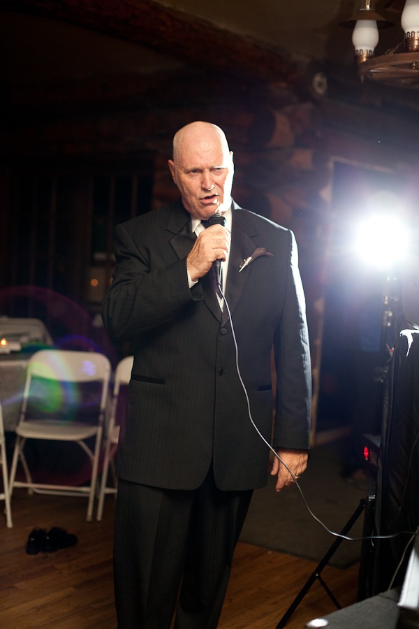 a groom talks into a microphone in front of a flash