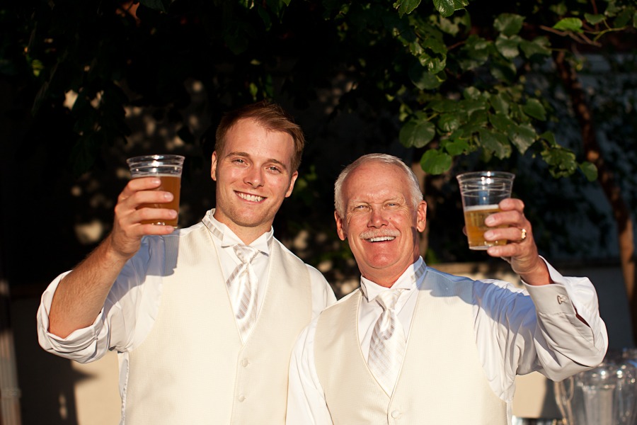 two men raise cups of beer towards the camera