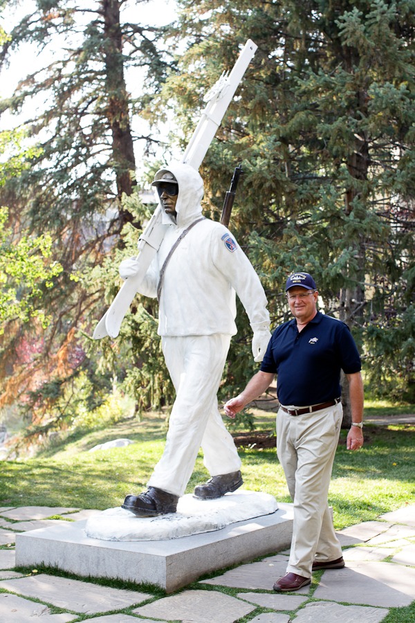 a man poses next to a statue of a skier