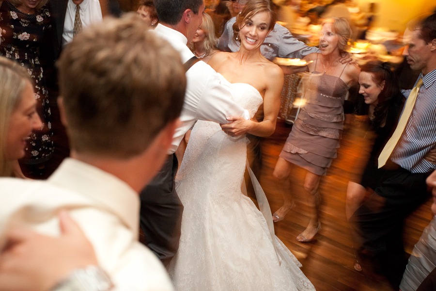 a bride dances with her groom in the middle of a circle of wedding guests