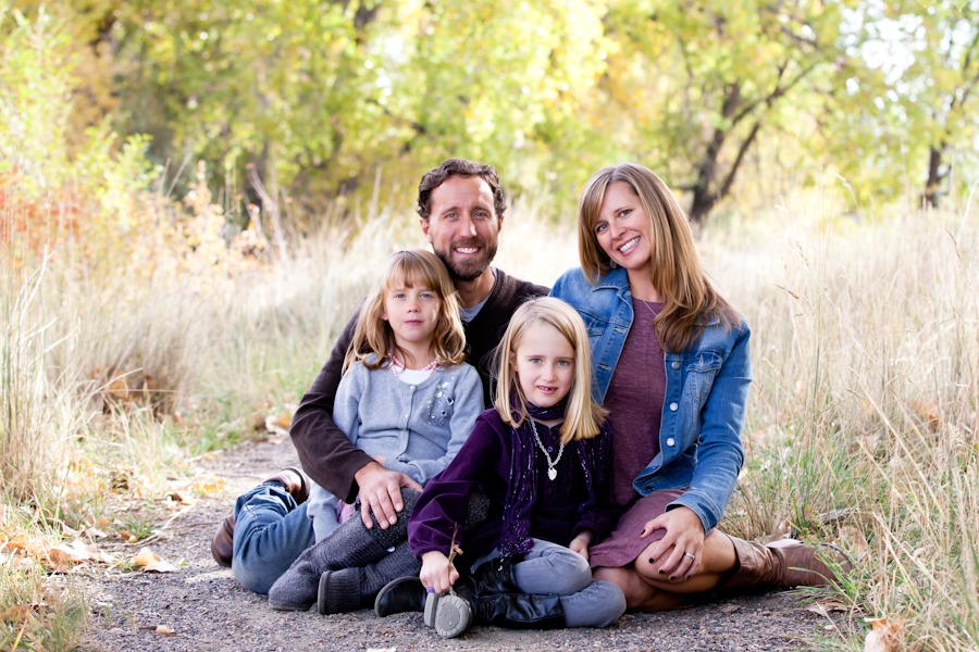 a family sits for portraits under fall trees