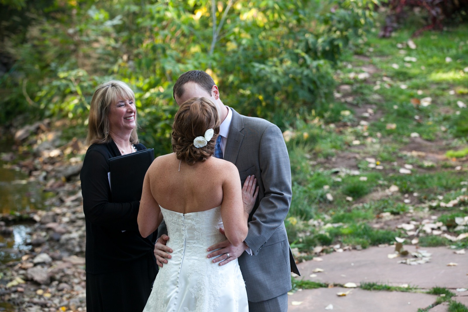 a wedding couple kiss in front of their officiant