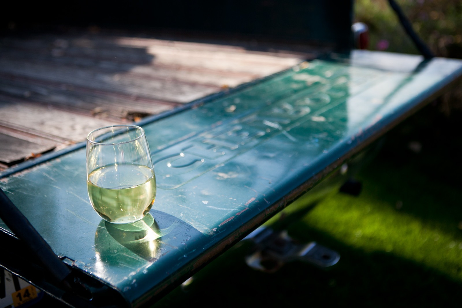 a glass of wine sits on the tailgate of an old truck