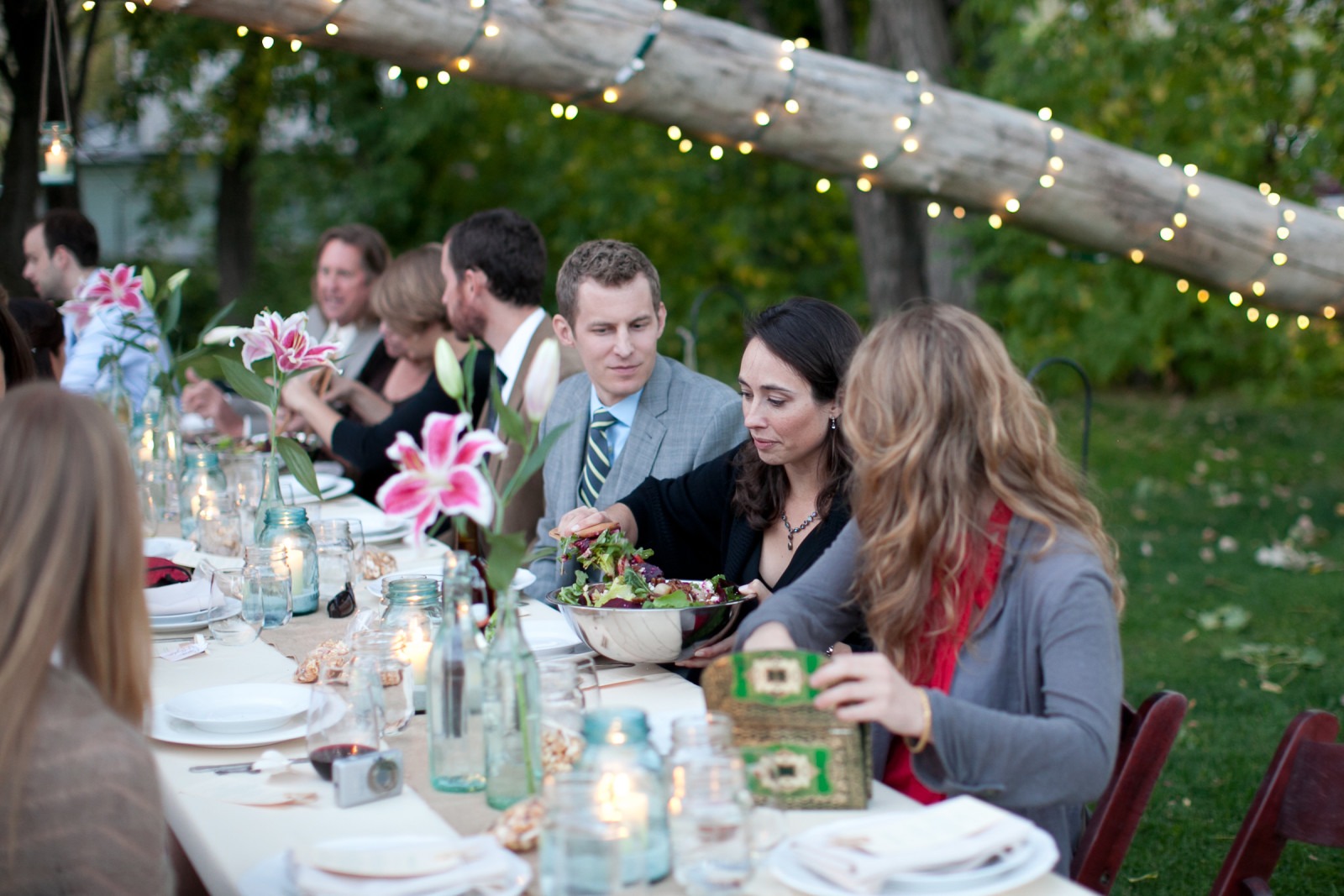 a woman dishes salad out of bar at a fancy table near a tree