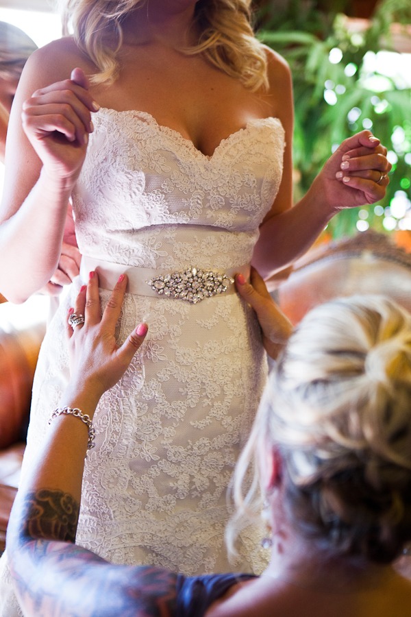 a woman ties a belt onto a bride
