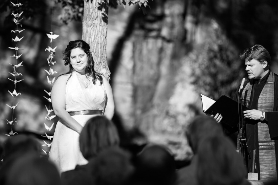 black and white image of a bride standing by a tree