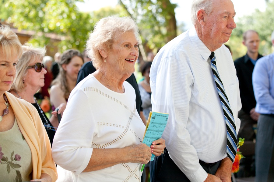 wedding guests stand and look towards a wedding couple while smiling