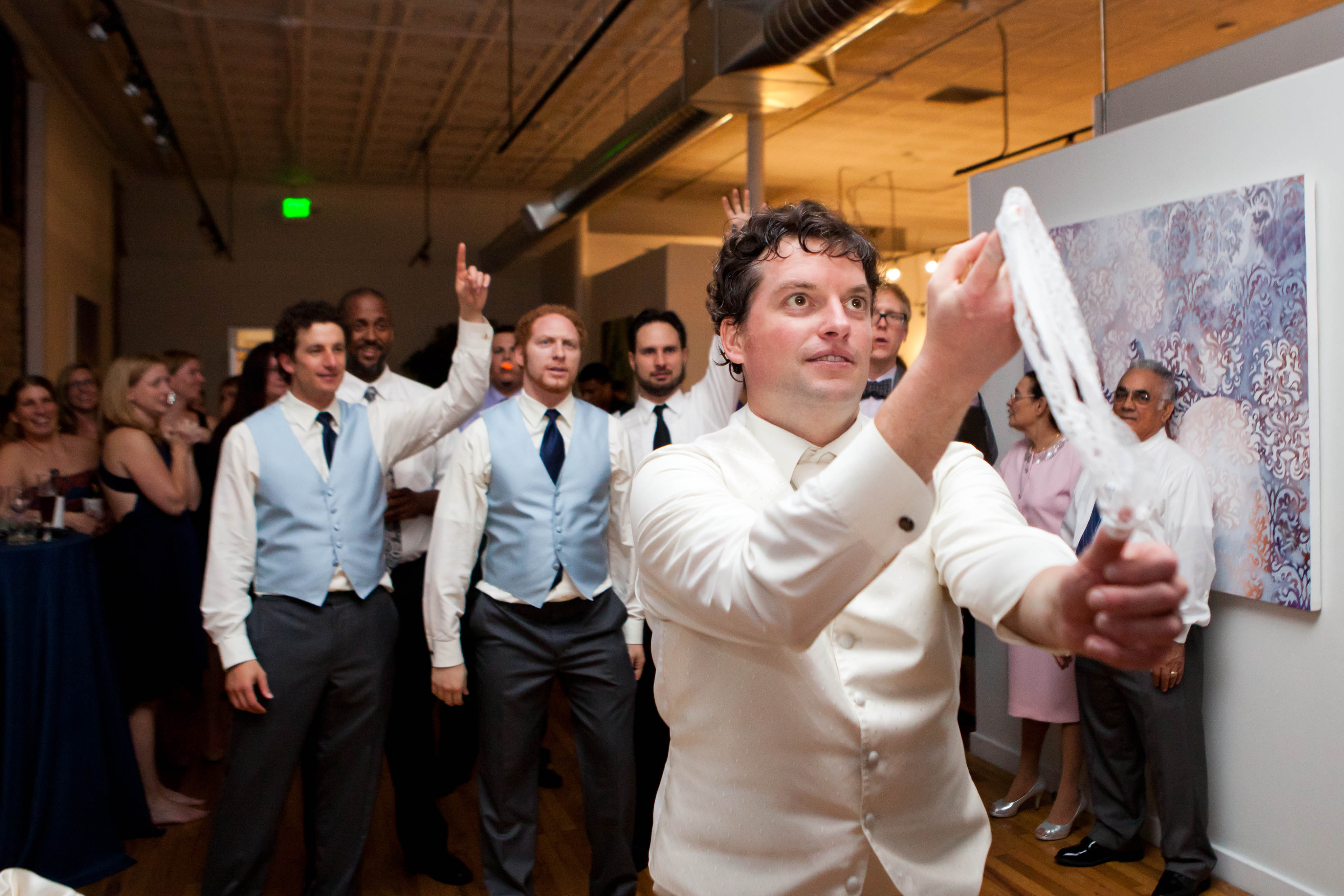 a groom is about to shoot a white garter belt towards a line of guys