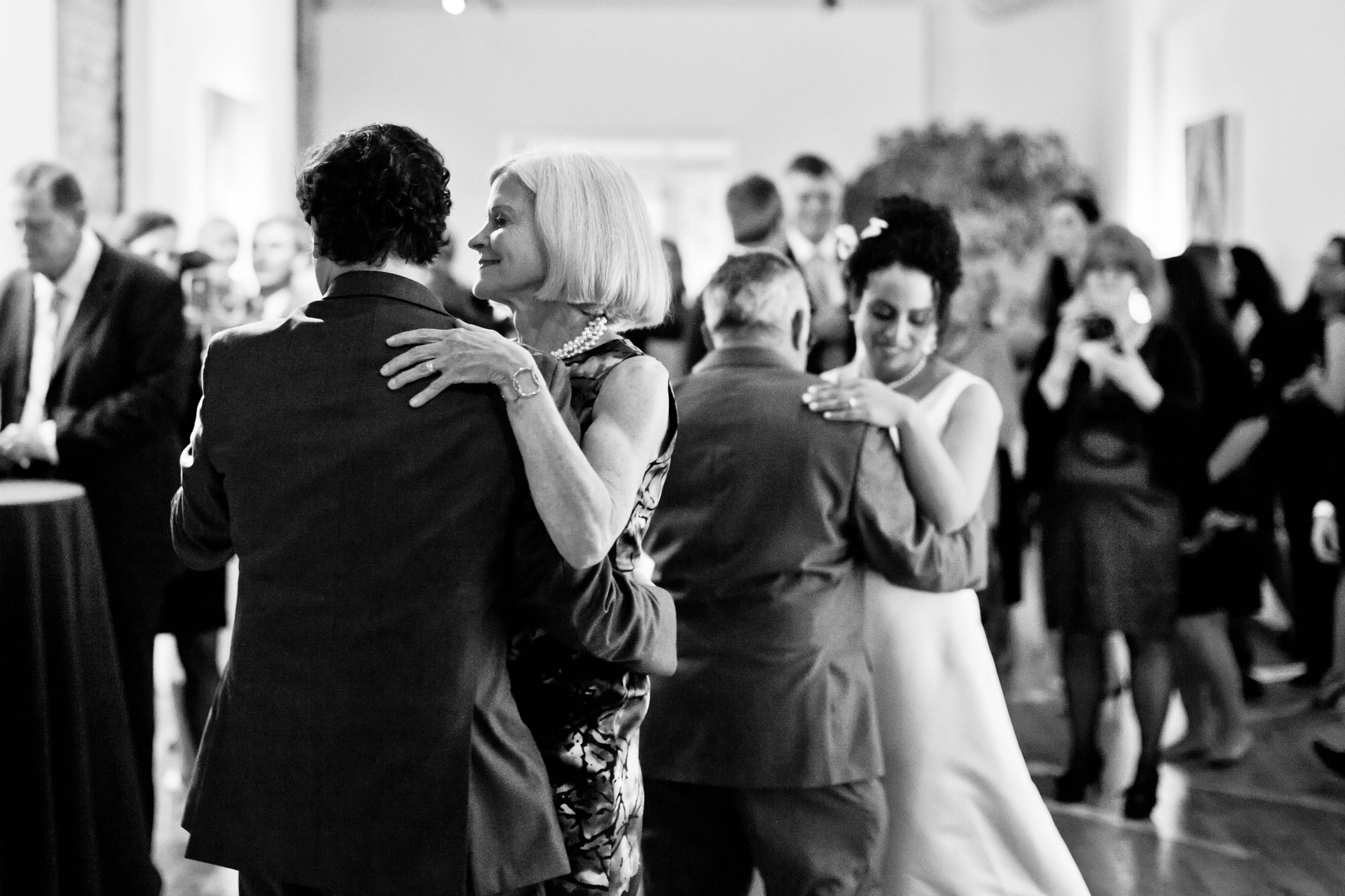 black and white photo of a groom and mom and a bride and dad dancing