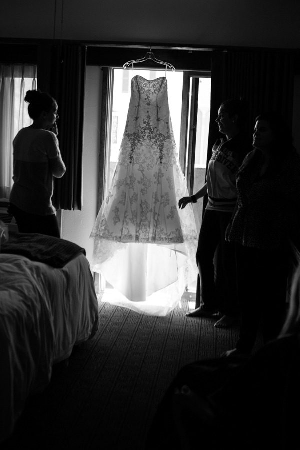 a wedding dress hangs in a hotel room