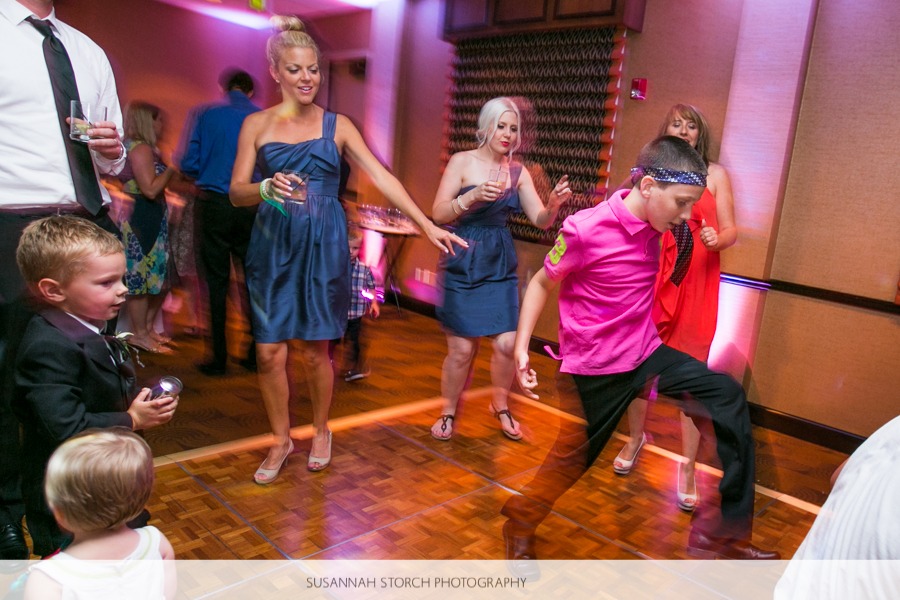 a boy in a hot pink shirt gets down on a dance floor in a long exposure photo