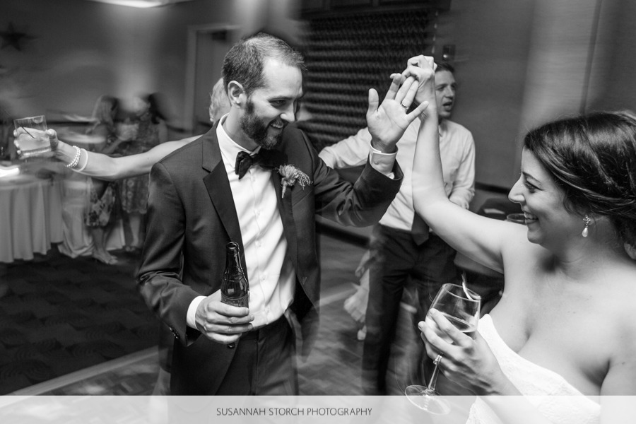 black and white photo of a groom spinning a bride while dancing