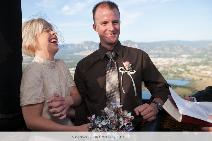 a bride and groom laugh while on a hot air balloon ride for their wedding ceremony