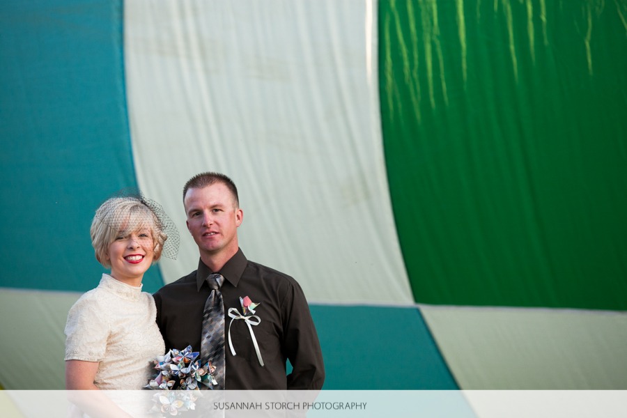 a bride and groom stand in front of a hot air balloon