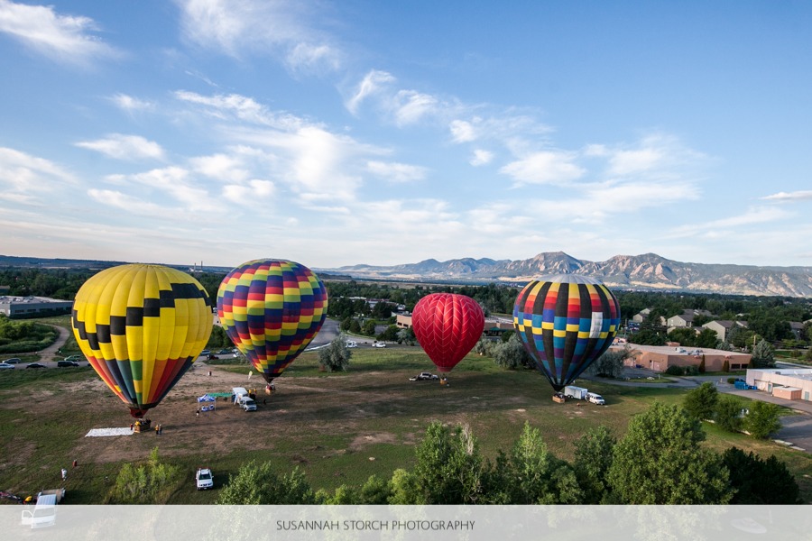 four hot air balloons in front of boulder's flatirons