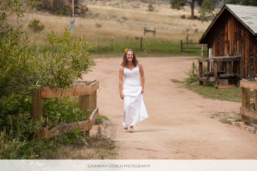 a bride walks down a dirt road while laughing