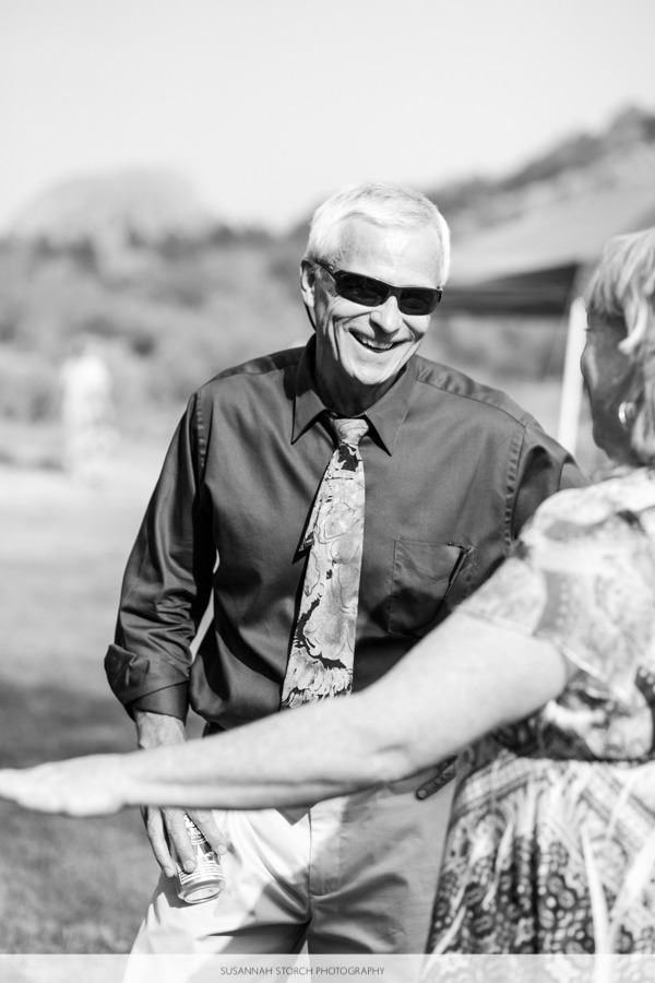 a man wearing sunglasses smiles while talking to a woman