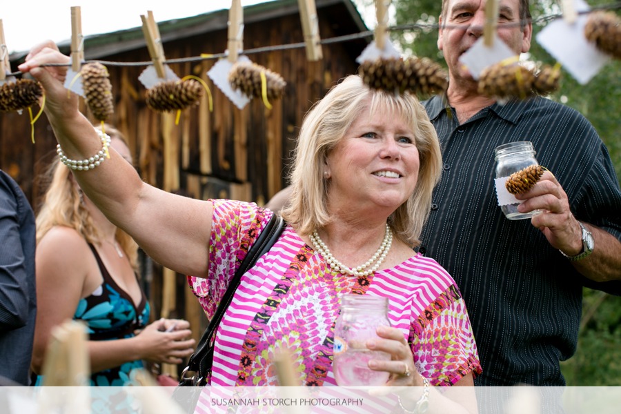a woman looks for her escort card which is hung on a clothes line with pinecones
