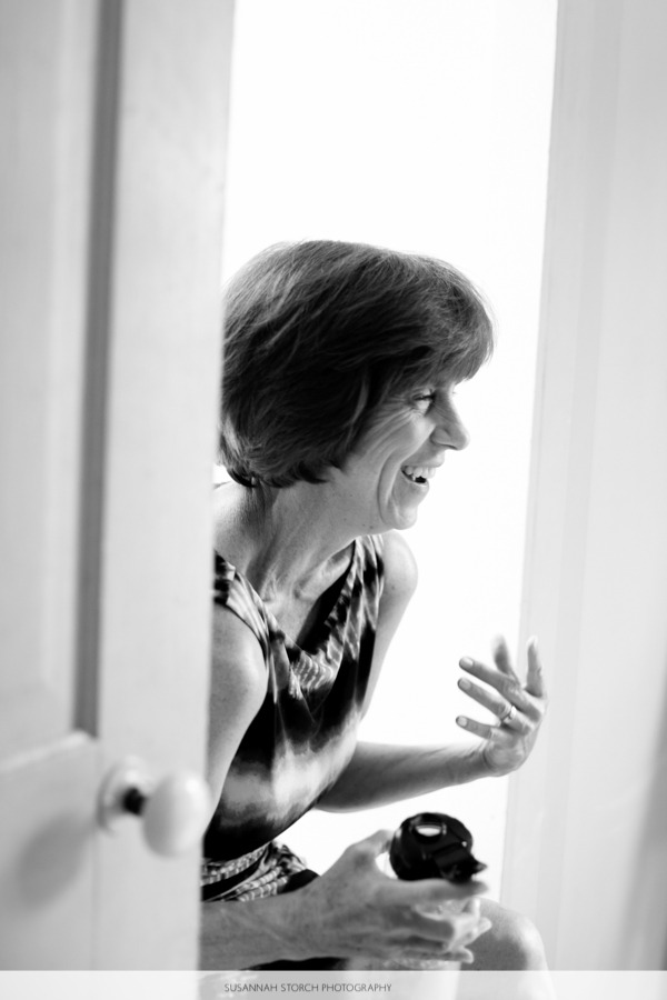 black and white photo of a mom laughing while sitting in front of a window