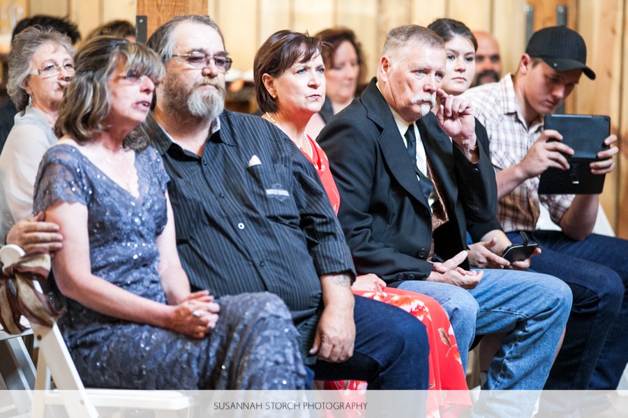 a row of seated wedding guests display different emotions