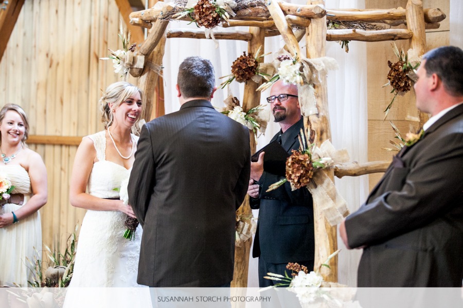 a bride smiles at her groom at an indoor barn wedding