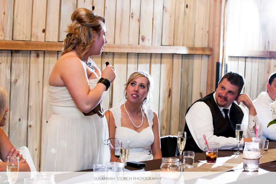 a woman gives a toast while a bride and groom watch and listen to her