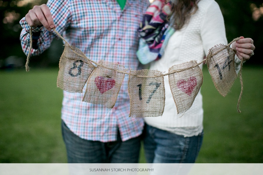 a couple hold up a burlap sign with their wedding date