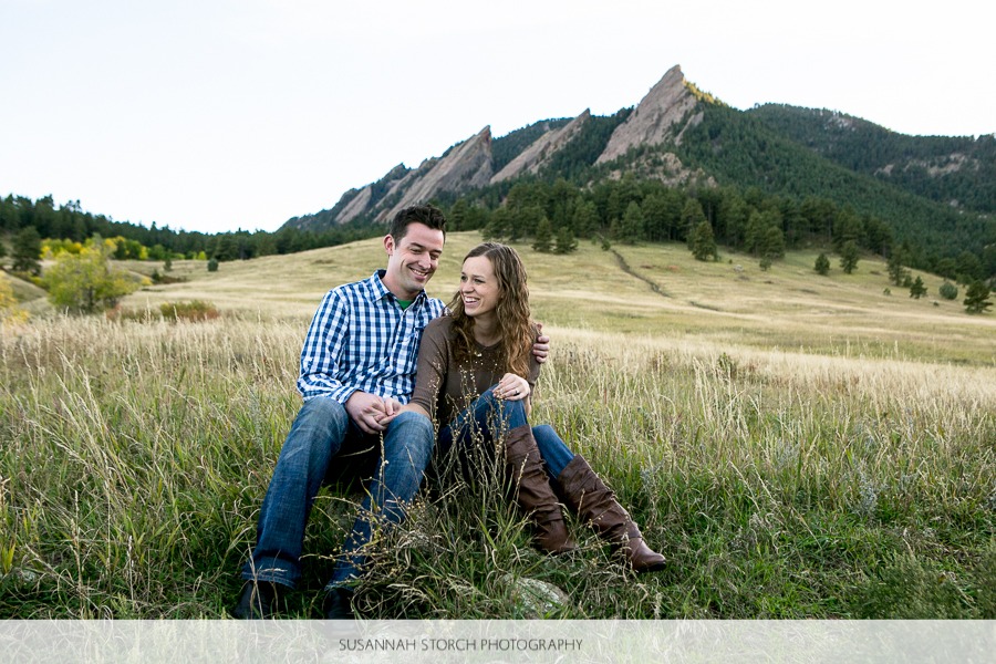 a man and woman sit in grass and laugh