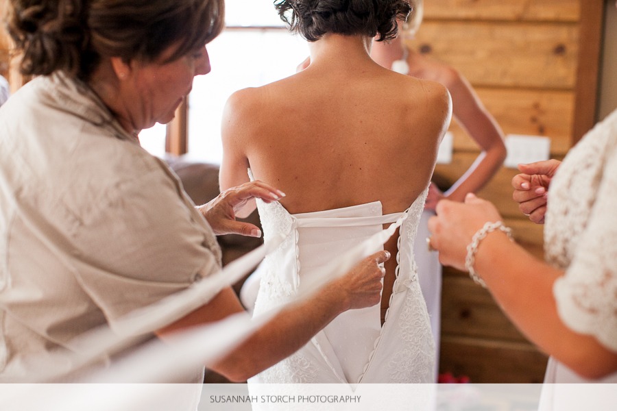 woman help a bride get into her wedding dress