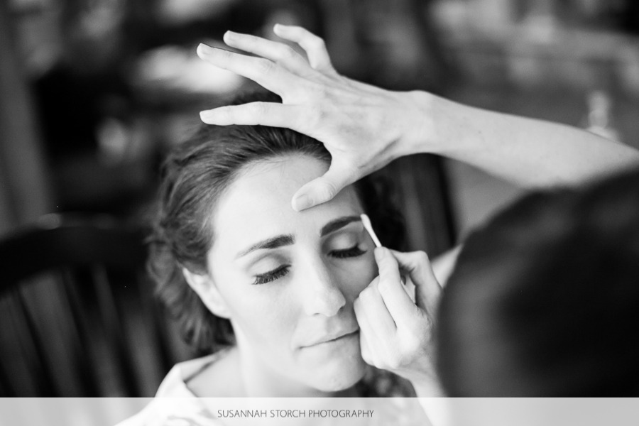 black and white photo of a woman getting her make up put on