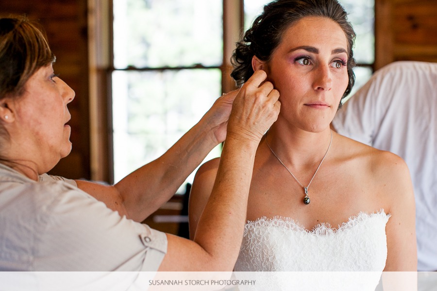 a woman puts earrings on an attractive emotional bride