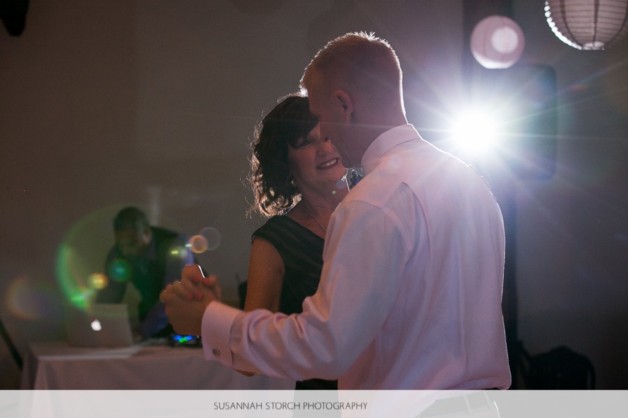 a mother and her son dance at a wedding in front of a flash flare