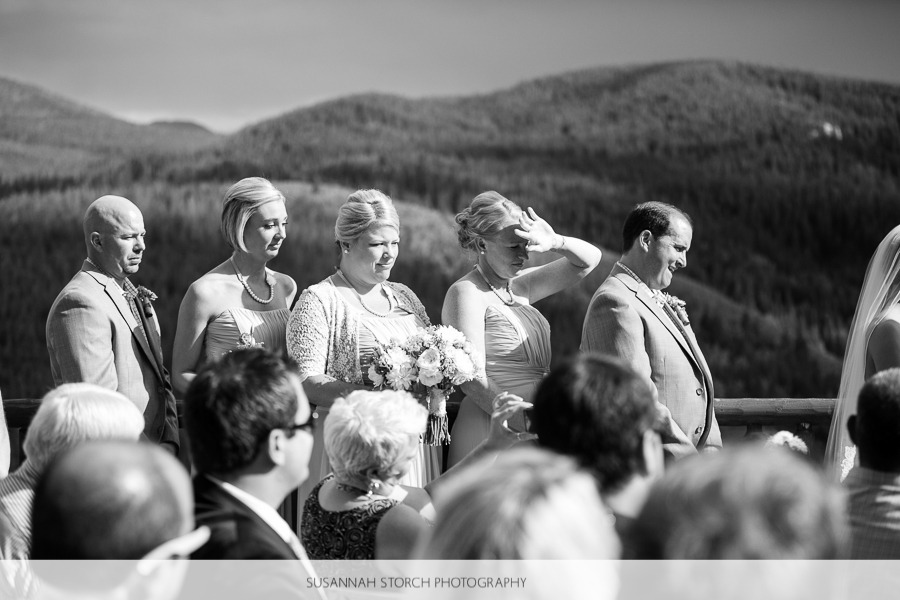 members of a wedding party stand and look towards the bride and groom under harsh light