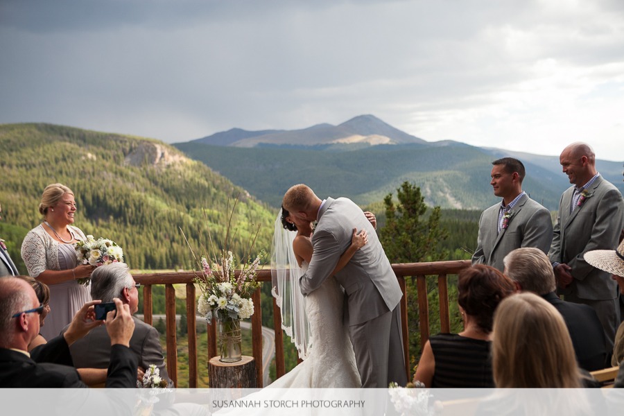 a bride and groom kiss under stormy skies