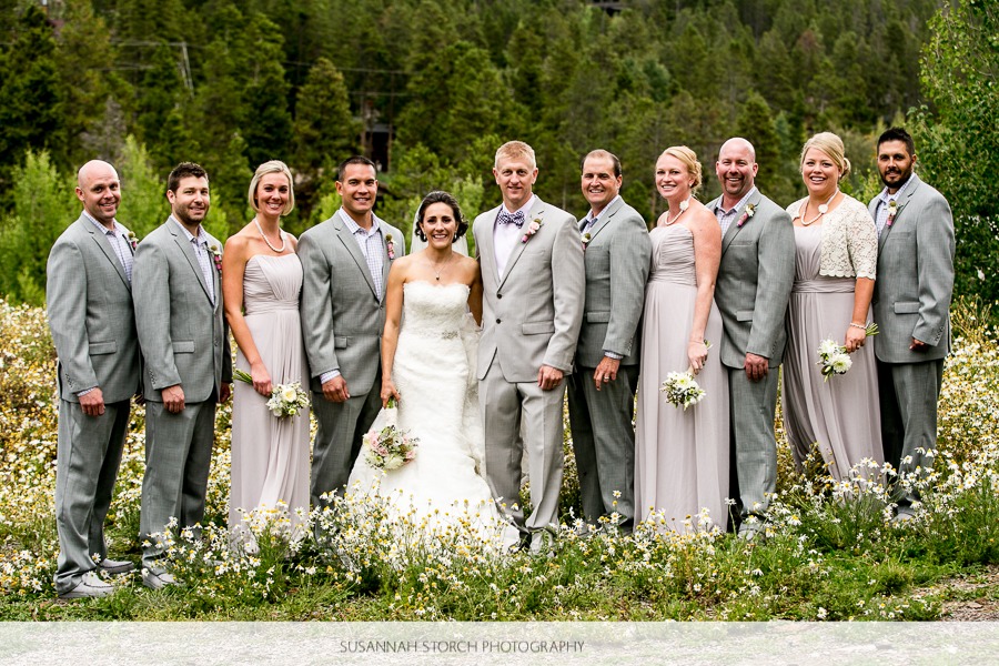 a wedding party lines up on a flowery field in front of green trees