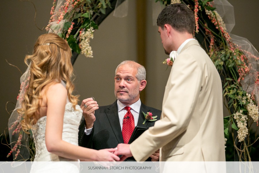 a man looks at a bride as he holds up a ring